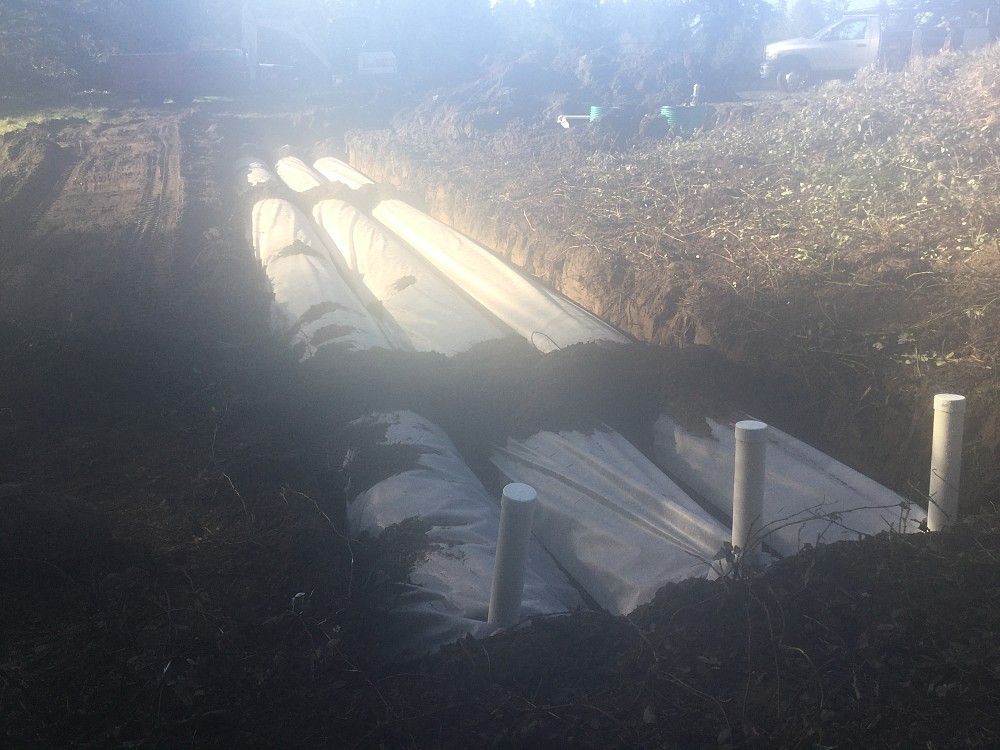 A row of pipes are being installed in a dirt field.