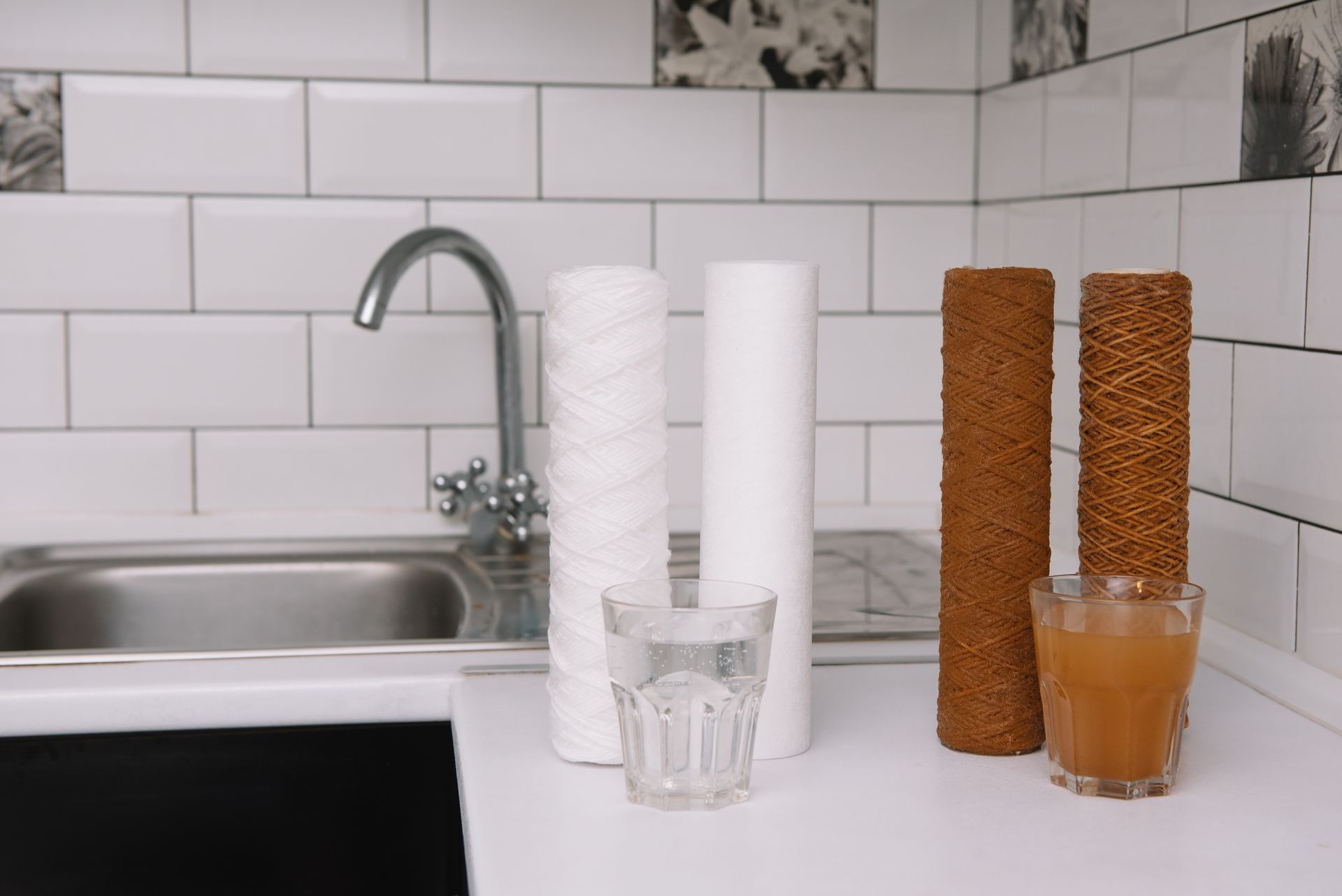 Kitchen counter with stacked paper towels, cork blocks, a glass of water, and a glass of juice by the sink