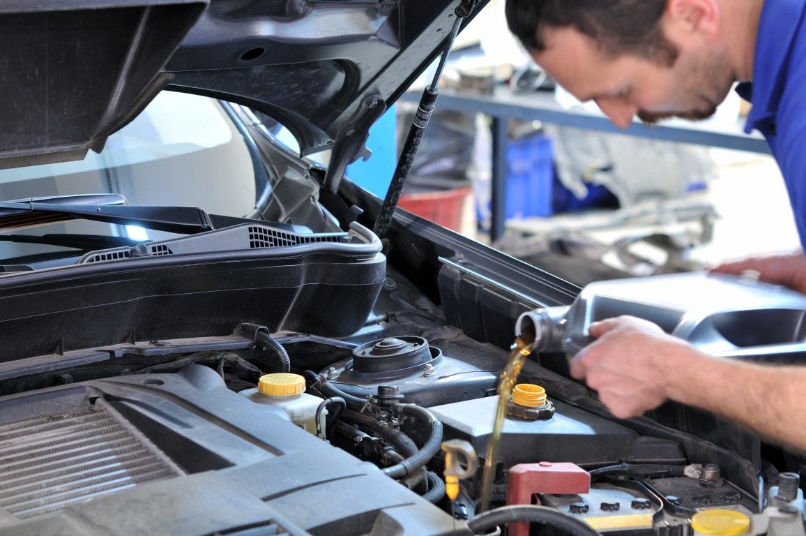 Mechanic inspecting an open car engine in a garage