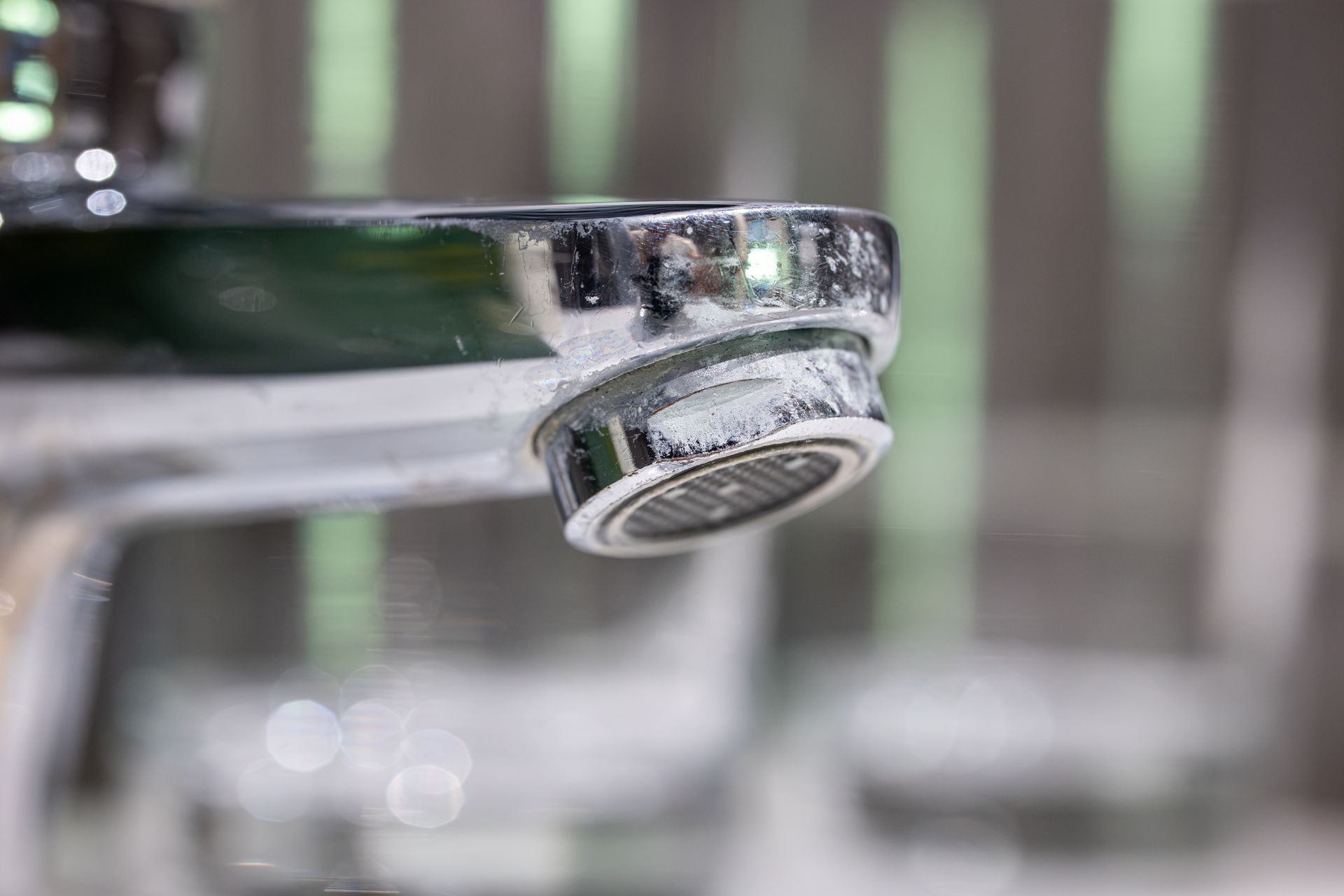 Close-up of mineral scale buildup on a chrome faucet aerator
