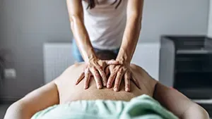 A person receiving a back massage while lying on a table in a room.