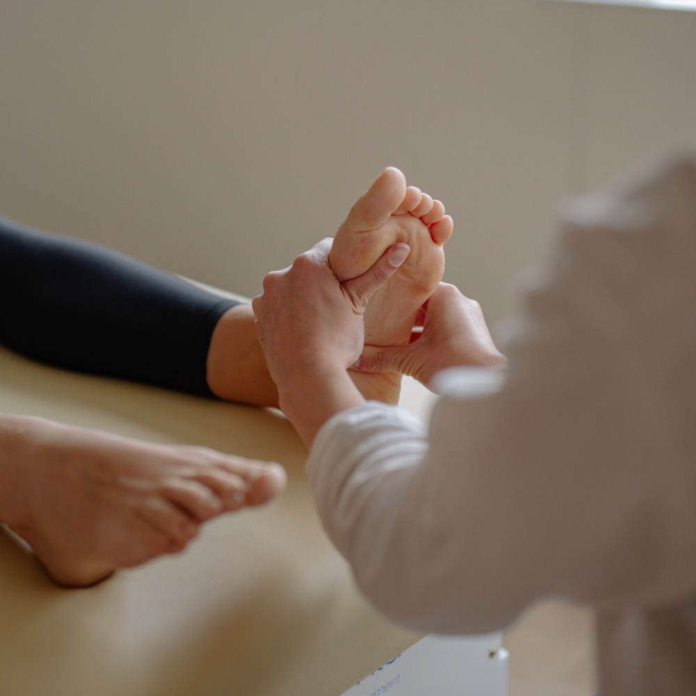 A person receives a foot massage while lying on a treatment table.