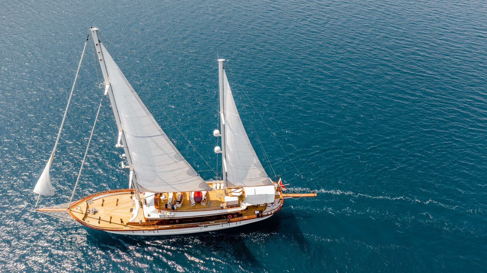 Sailboat with white sails gliding across deep blue water