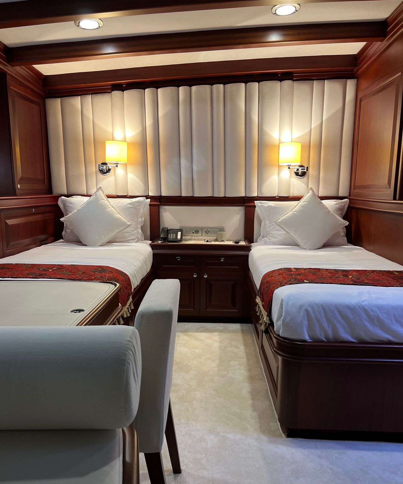 Luxury bedroom cabin with two twin beds, warm wood paneling, and bedside lamps