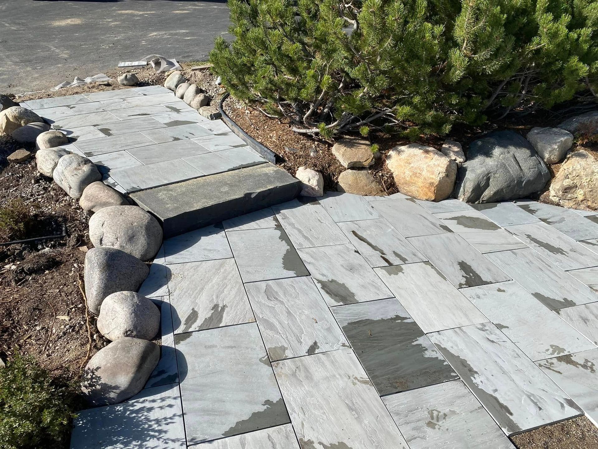 Stone walkway with gray pavers curving through desert landscaping and shrubs