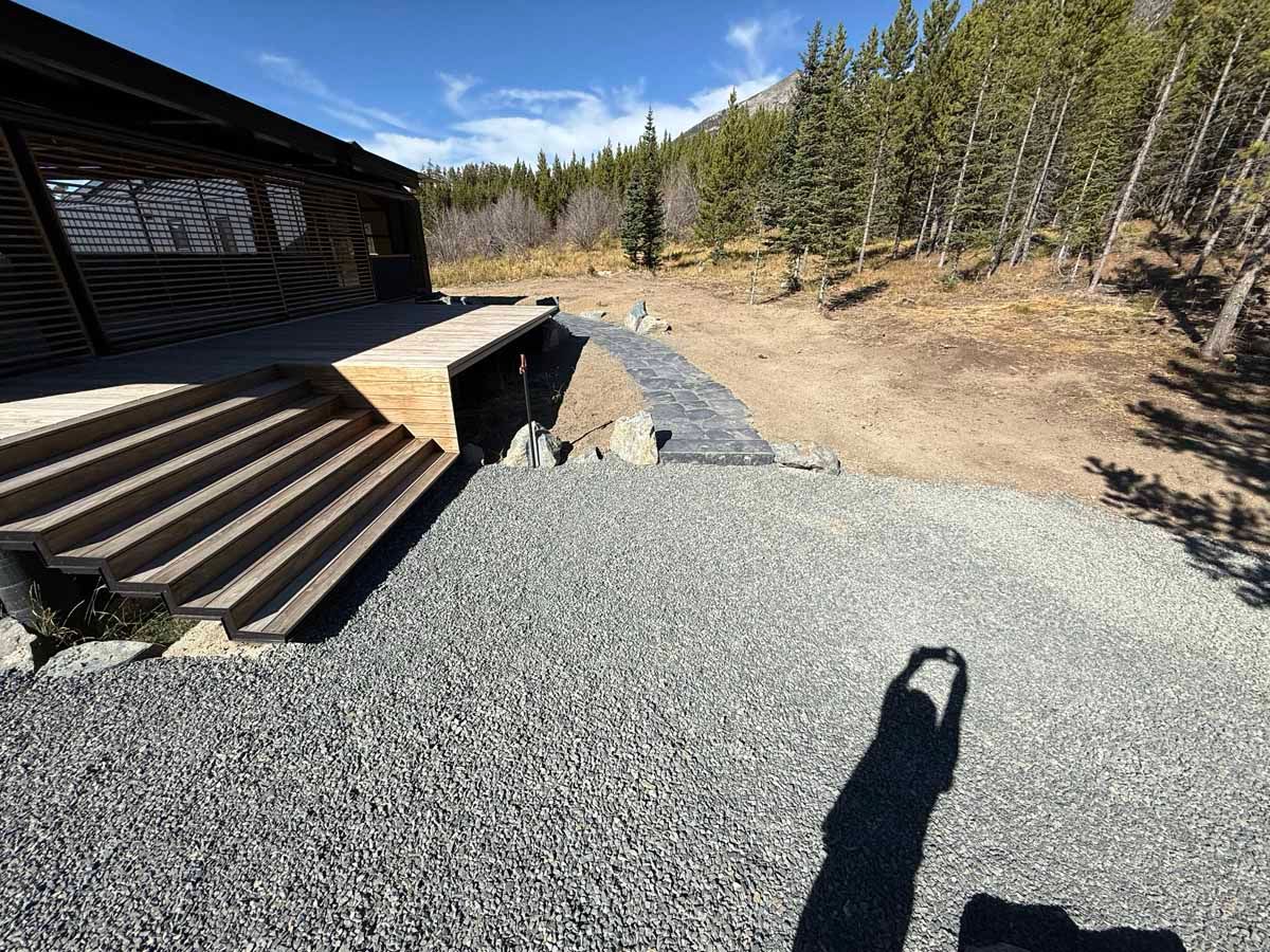 Gravel path beside wooden steps and pavilion in a sunny forest clearing