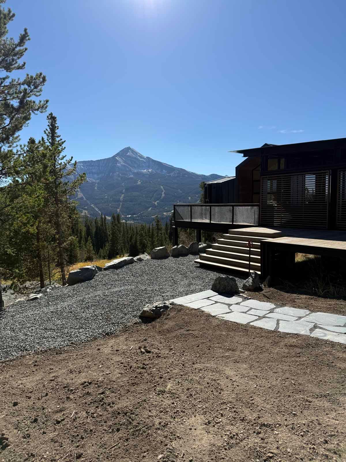 Mountain view from a cabin deck with pine trees and a clear blue sky