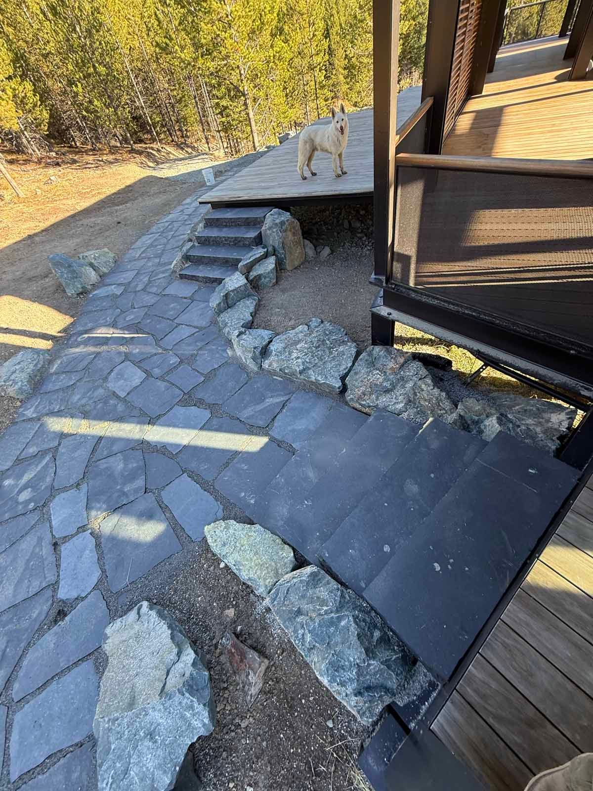 Damaged roof shingles and debris scattered around a house exterior near a wooden deck