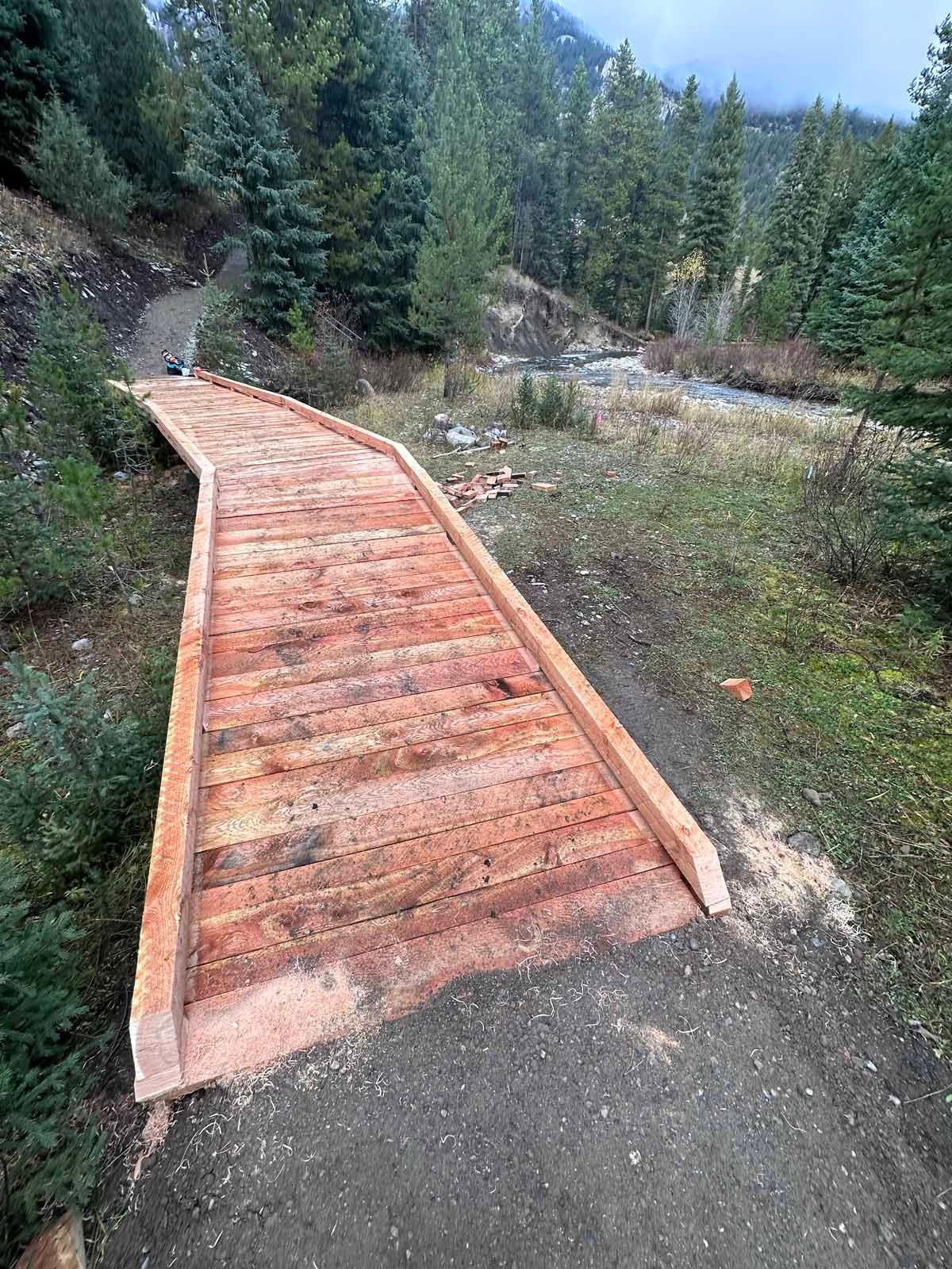 Curved wooden boardwalk through a rocky, forested trail.