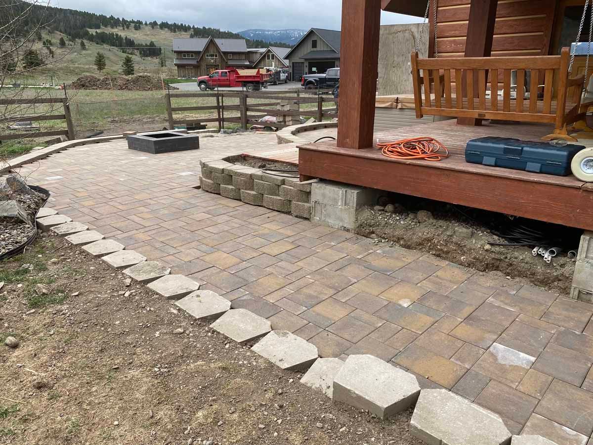 Stone walkway beside a wooden cabin porch overlooking a rural mountain landscape