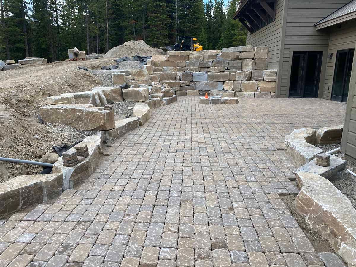 Stone-paved patio with terraced rock landscaping and a house exterior in the background