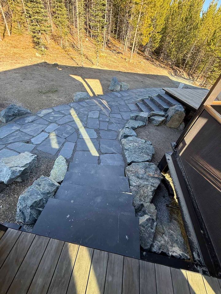 Broken stone patio and steps beside a building, with a yellow line painted on the ground.
