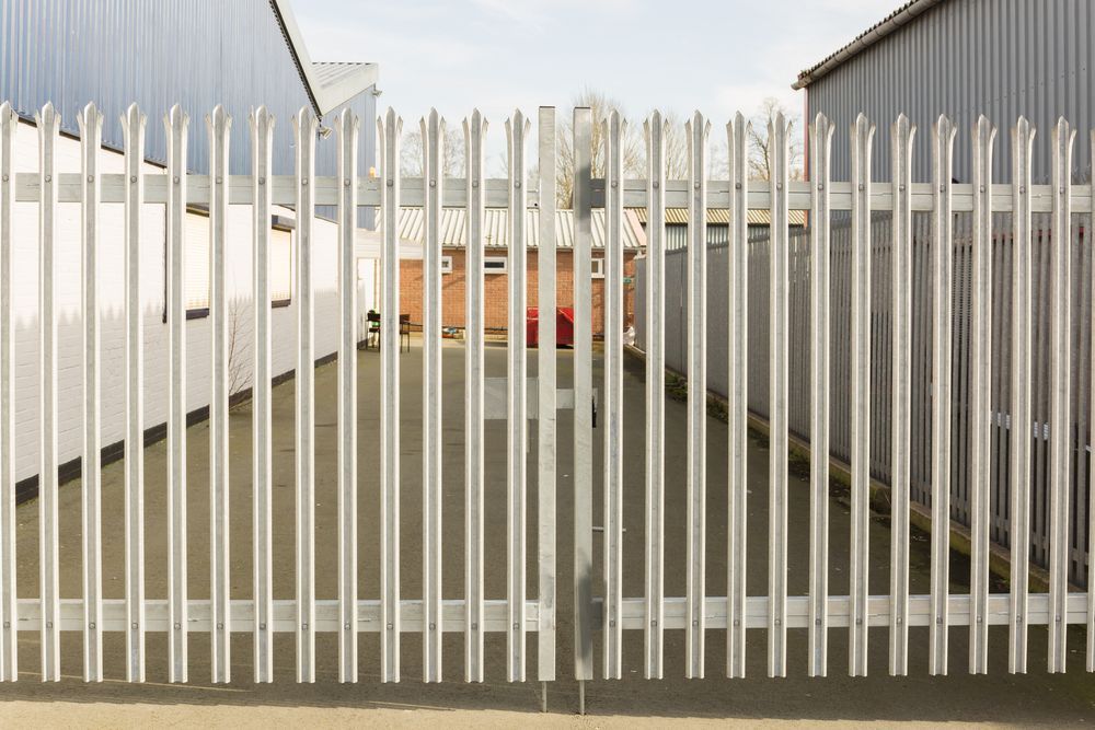 Closed Metal Gate With White Vertical Bars Between Two Buildings — Everyday Maintenance Pty Ltd In Beaconsfield, QLD