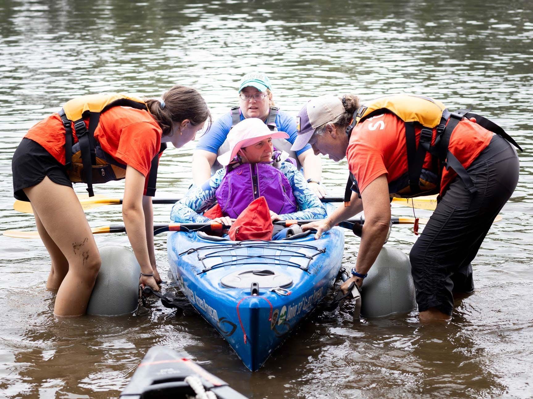 Two All Out Adventures staff assist a two people in a kayak in the water.