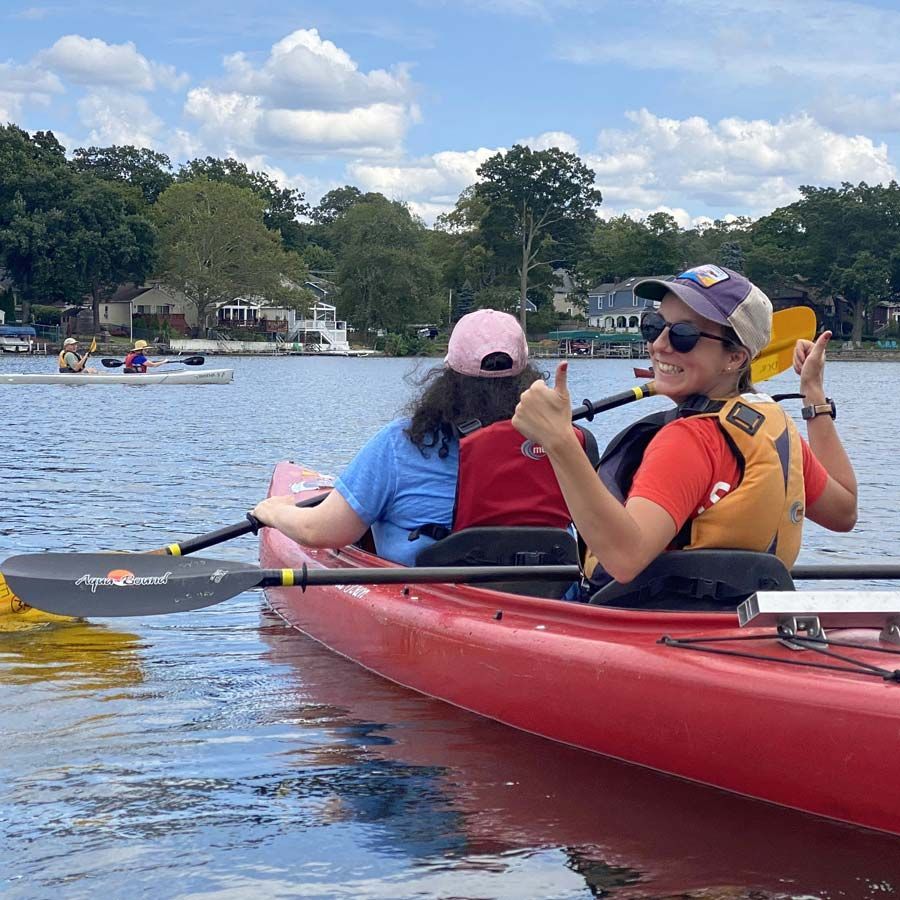 An All Out Adventures volunteer paddles with a participant in a kayak on a river.