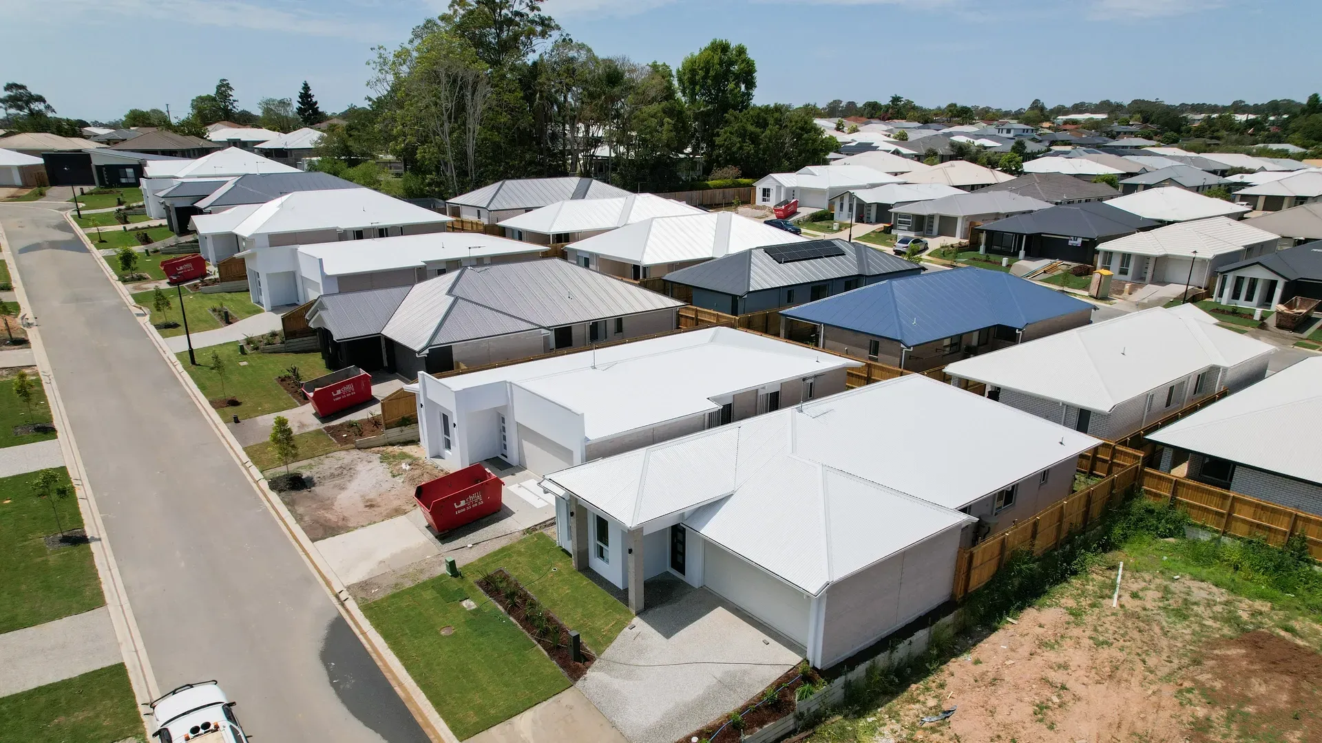 Aerial view of a suburban neighborhood with many houses and driveways on a sunny day. — Smart Metal Roofing in Coomera, QLD