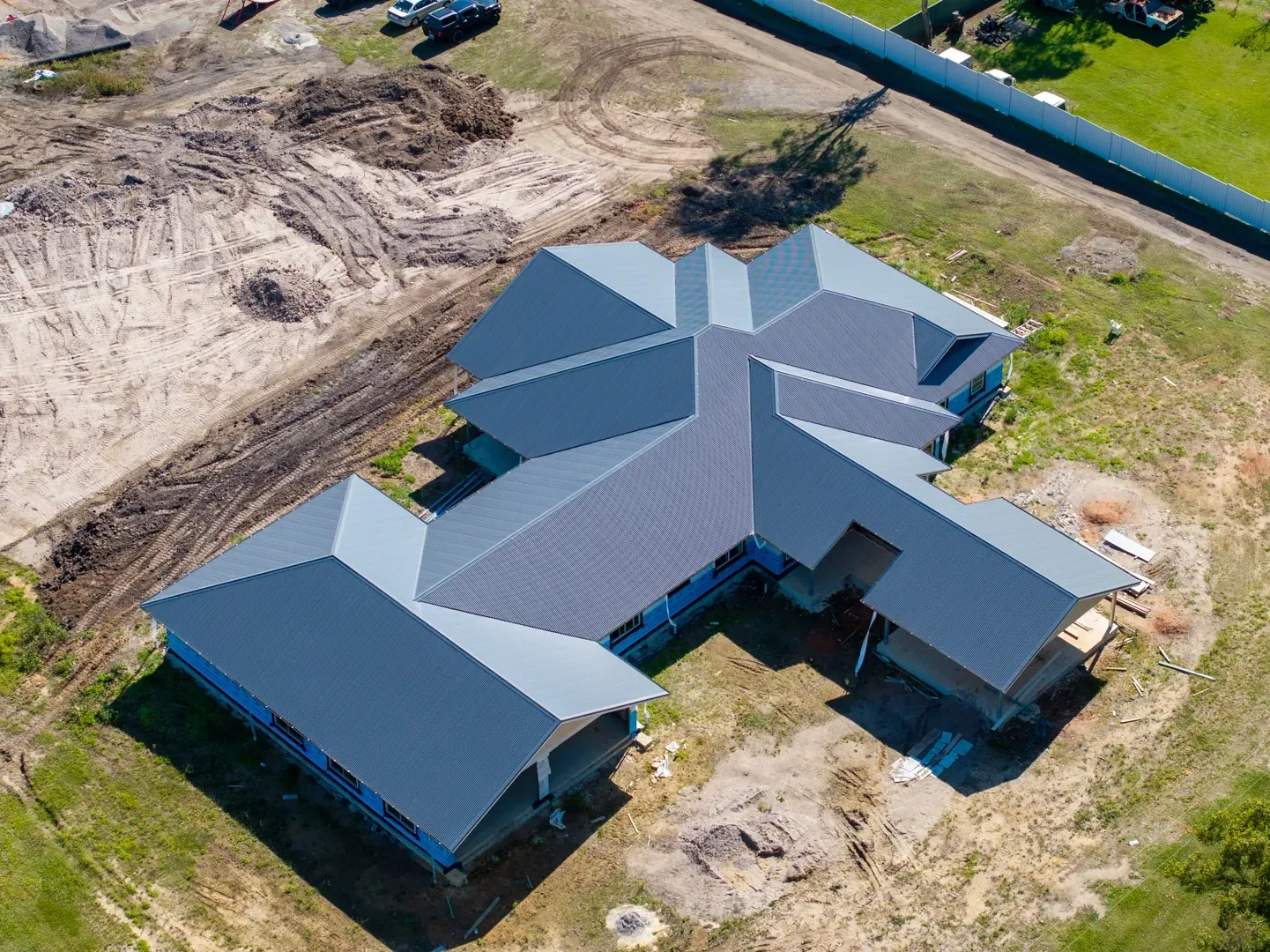 Aerial view of a partially constructed house with a gray metal roof on a grassy plot. — Smart Metal Roofing in Coomera, QLD
