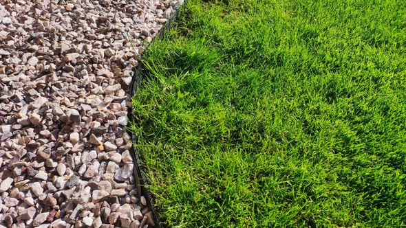 Green grass next to a bed of light brown gravel.