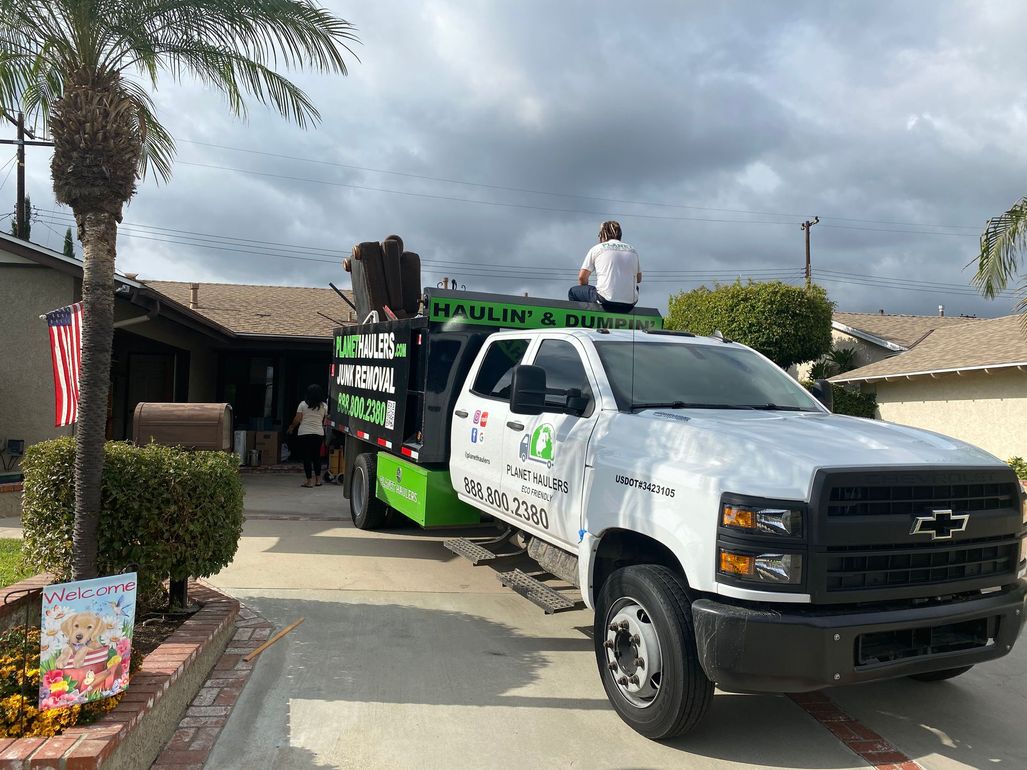A white truck is parked in front of a house with a man sitting on top of it.