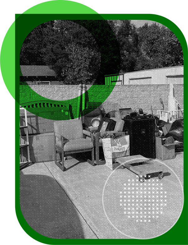 A black and white photo of a couch and chairs on a sidewalk.