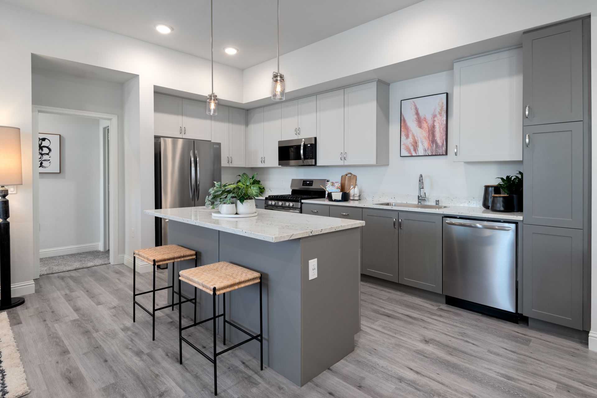 Modern kitchen with gray cabinets, stainless steel appliances, and a white island.