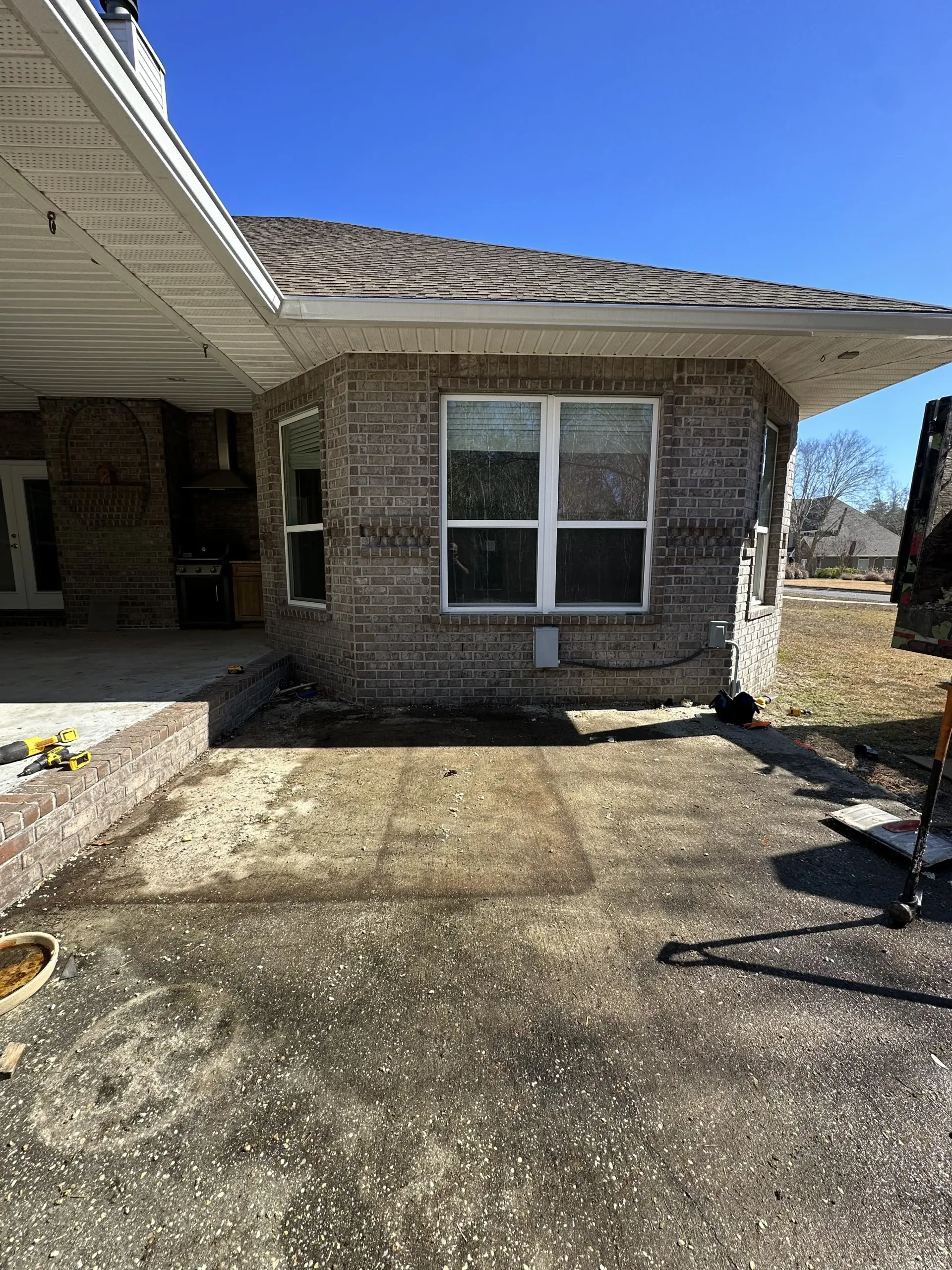 Brick house entrance with concrete walkway, double window, and white roof overhang