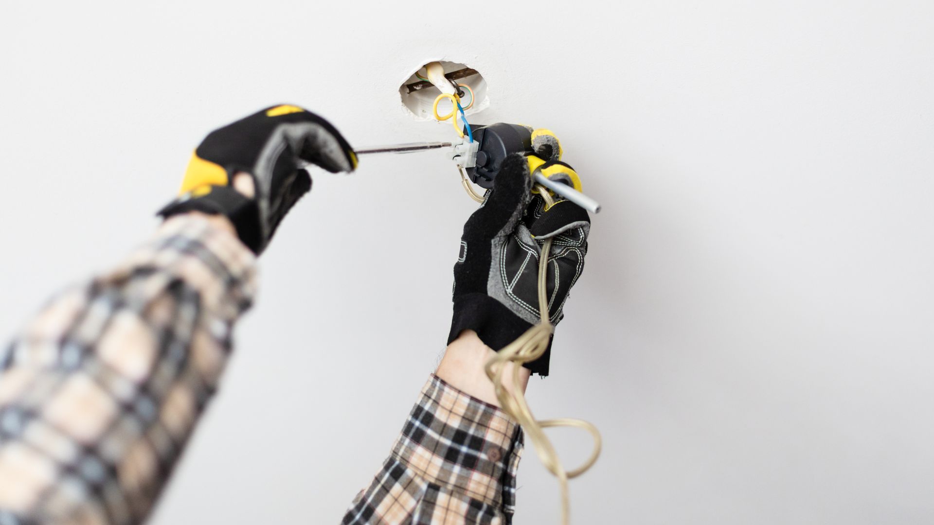 A person is installing a light fixture on a wall.