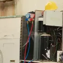 Open electrical panel with gauges, wiring, and red and blue hoses in a workshop