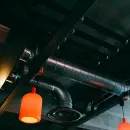 Industrial ceiling with silver ductwork and two orange hanging pendant lights