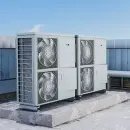 Outdoor HVAC units on a rooftop, light gray metal with large fans and a blue sky background