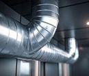 Shiny metal ventilation ducts running across a ceiling in an industrial interior