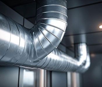 Shiny metal ventilation ducts running across a ceiling in an industrial interior