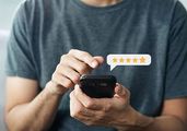 Person typing on a smartphone with a 5-star rating icon floating above it.
