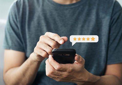 Person typing on a smartphone with a 5-star rating icon floating above it.