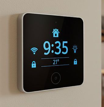 Wall-mounted smart thermostat showing 9:35, 21°, and Wi‑Fi, lock, and home icons on a black screen