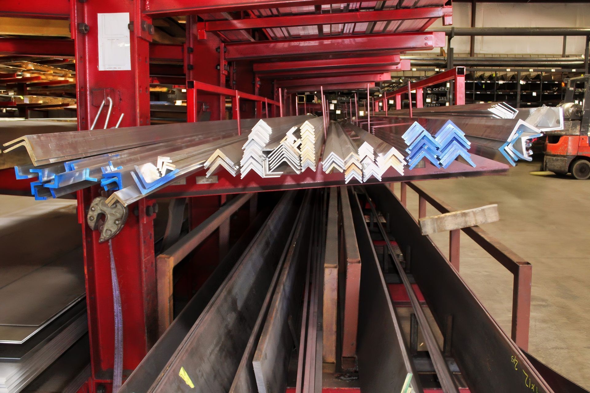 Metal angle iron and beams on red storage racks in a warehouse.