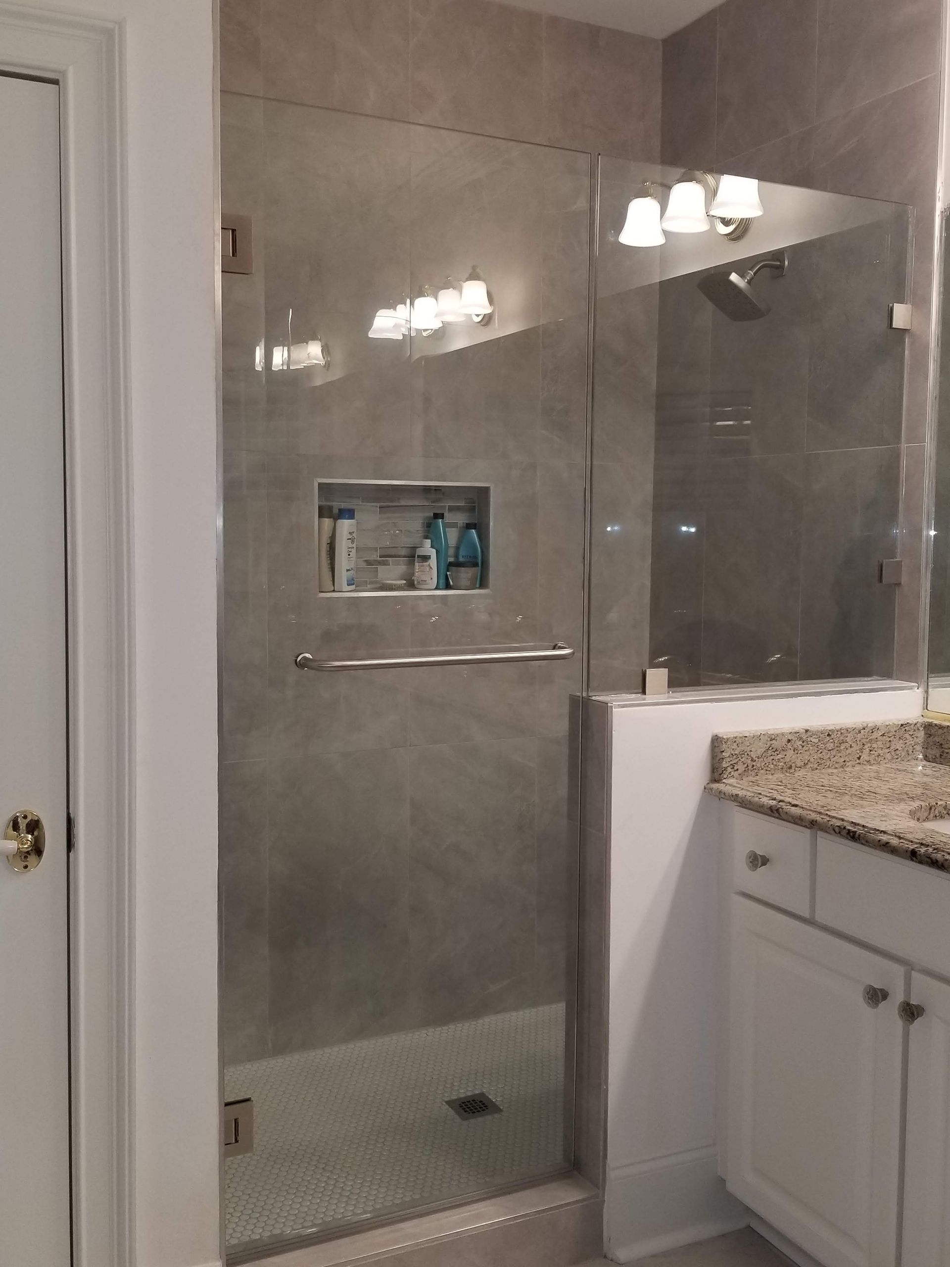 A bathroom with a walk in shower and a sink
