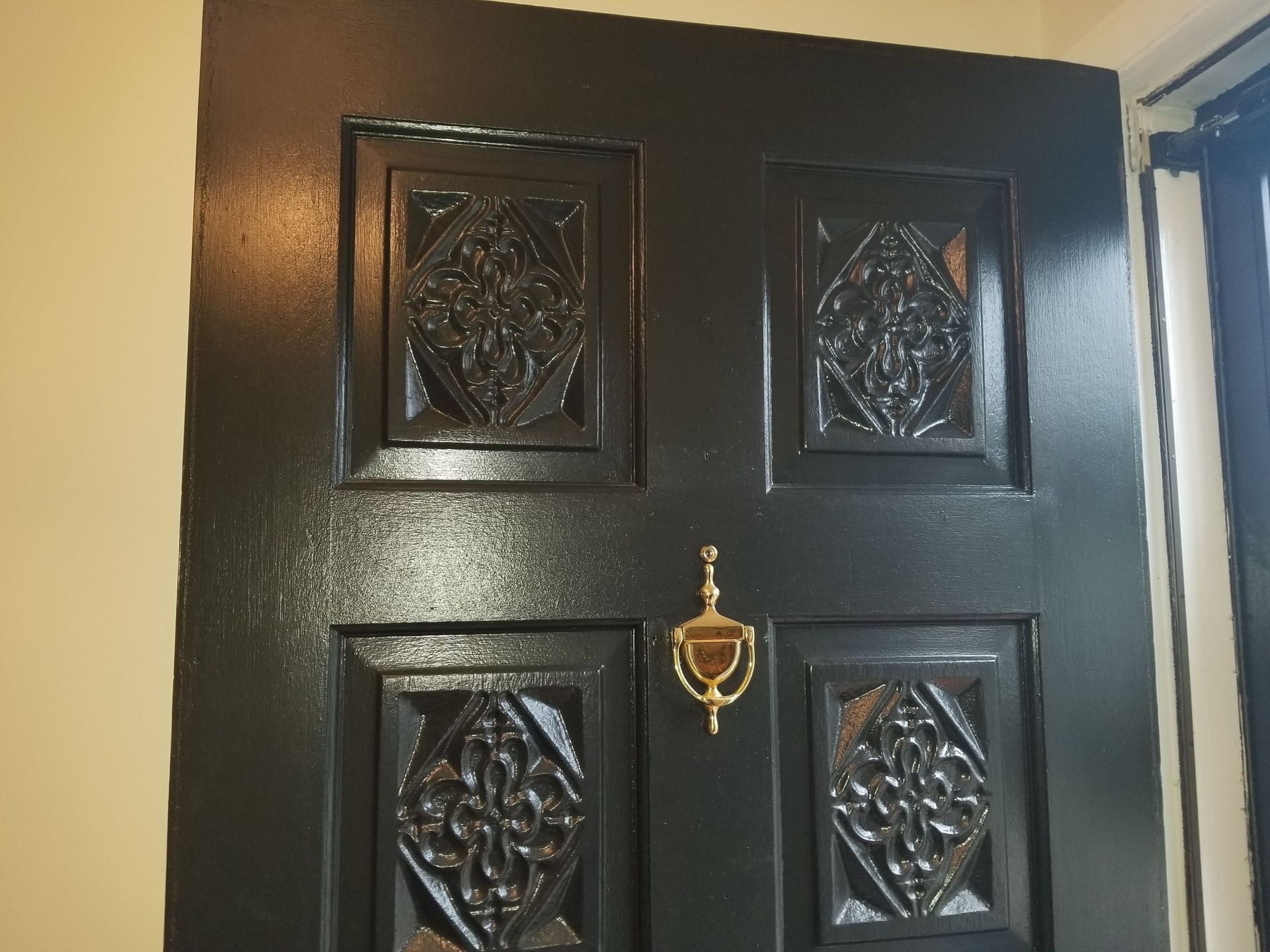 A black door with a gold door knocker on it