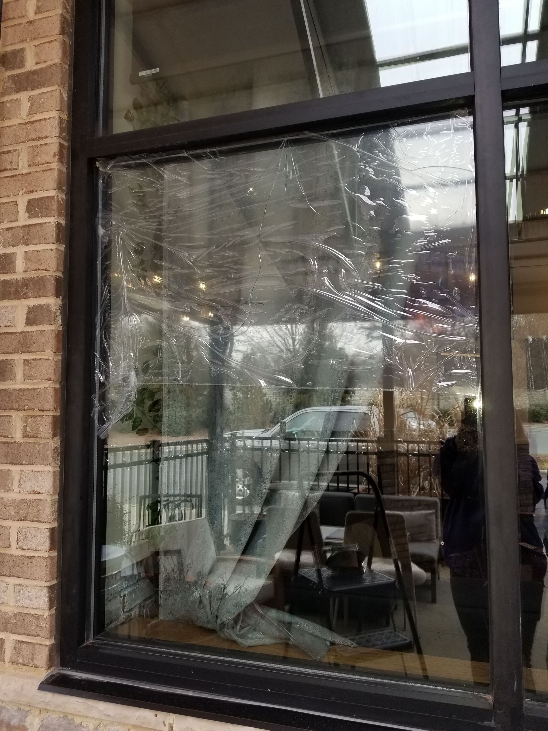 A broken window in a building with a plastic cover on it.