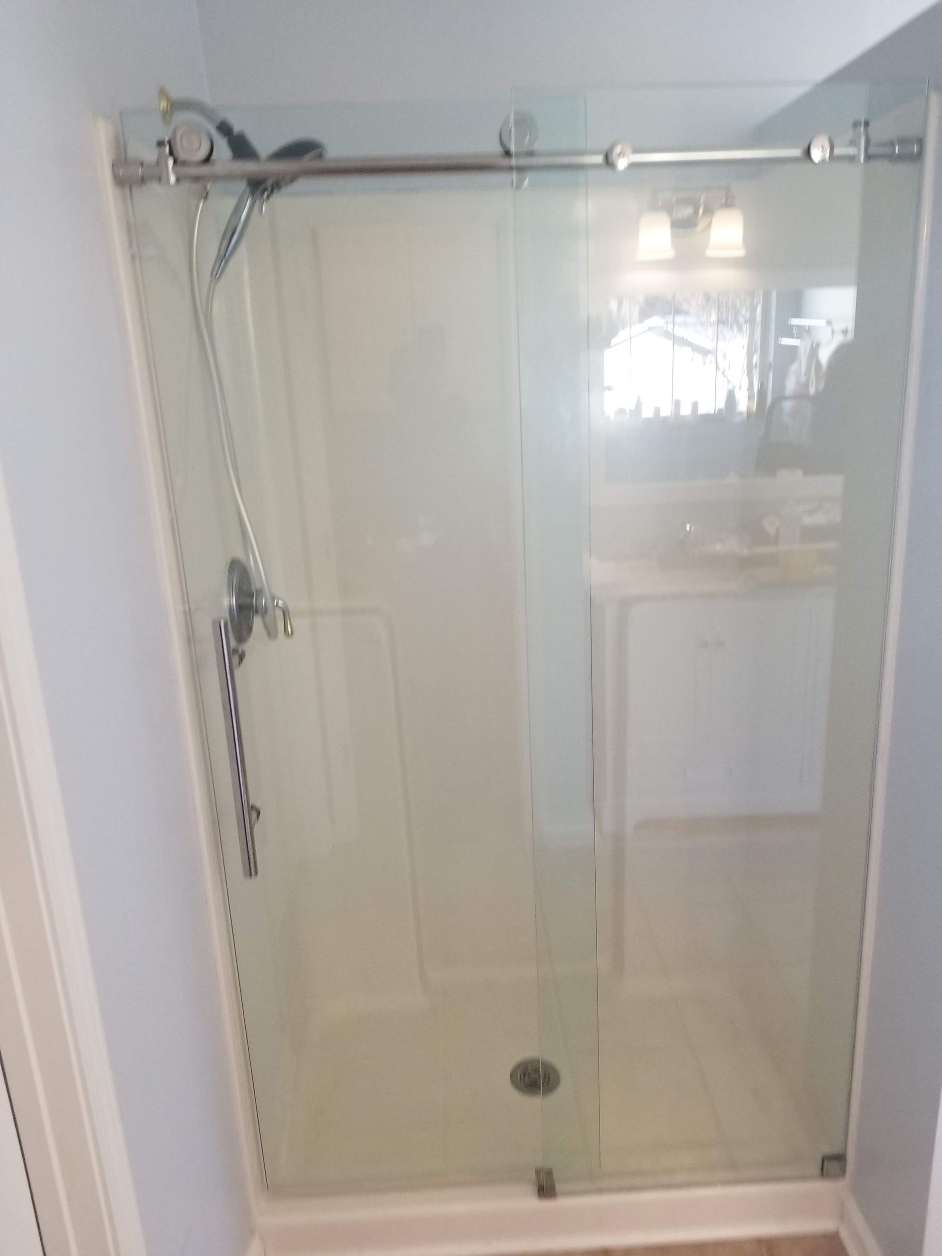 A bathroom with a sliding glass shower door and a shower head.