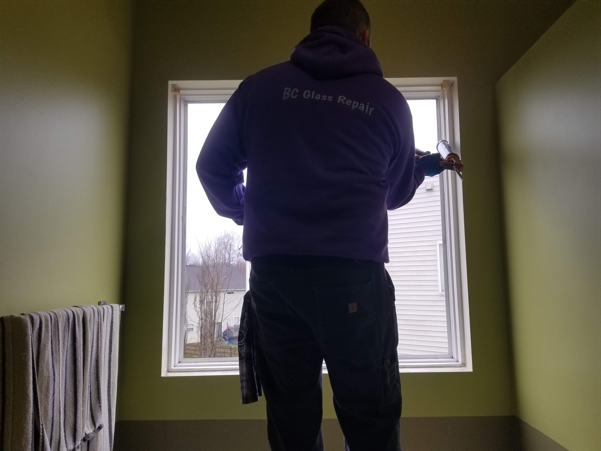 A man in a purple hoodie is cleaning a window