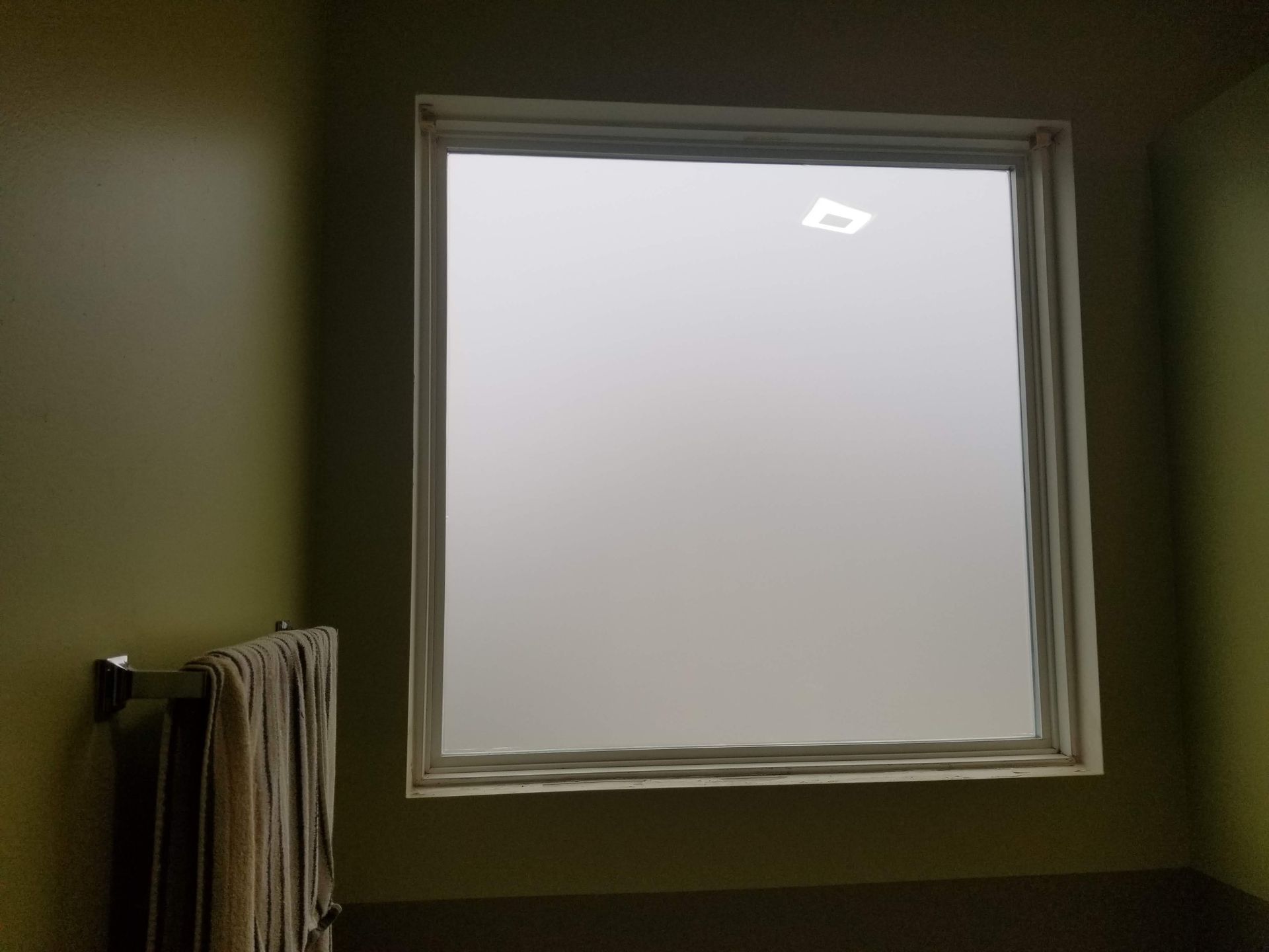 A bathroom with a window and a towel rack.