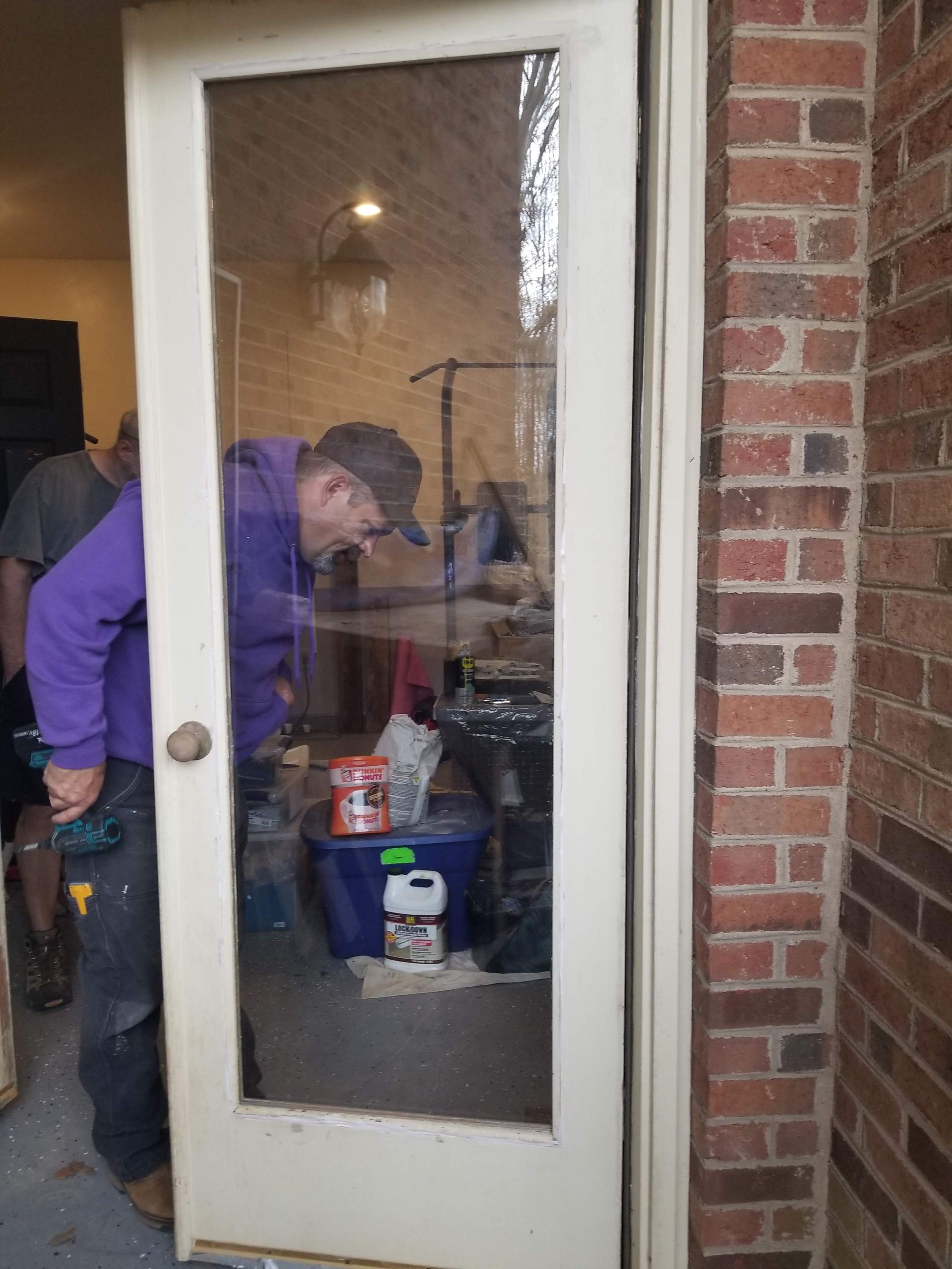 A man in a purple hoodie is standing in front of a glass door.