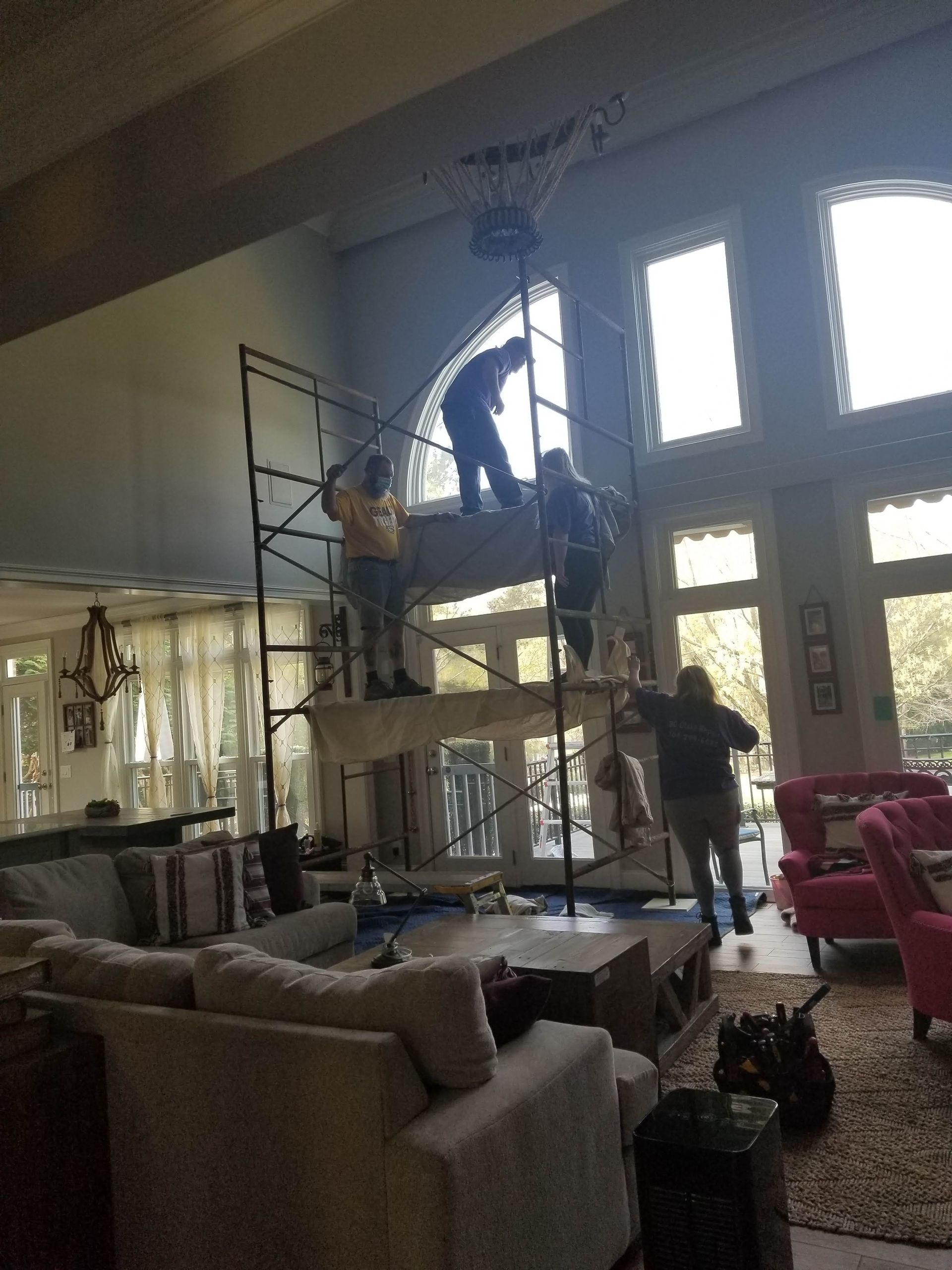 A man is standing on a scaffolding in a living room.