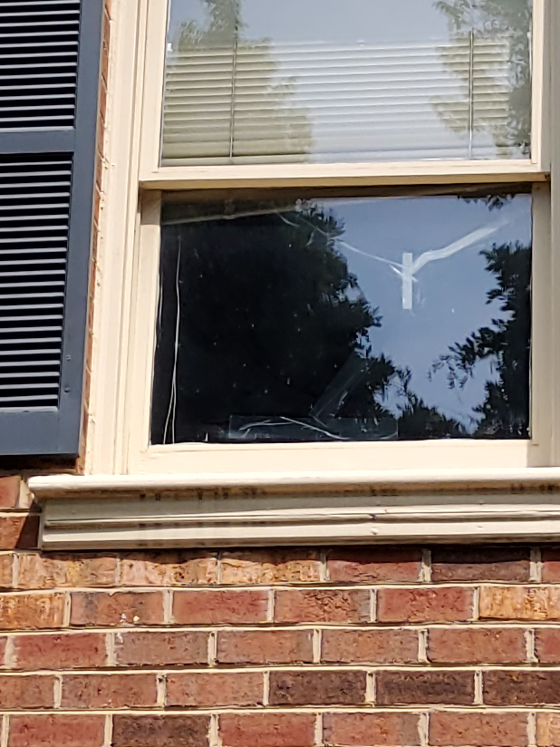A brick building with a broken window and shutters