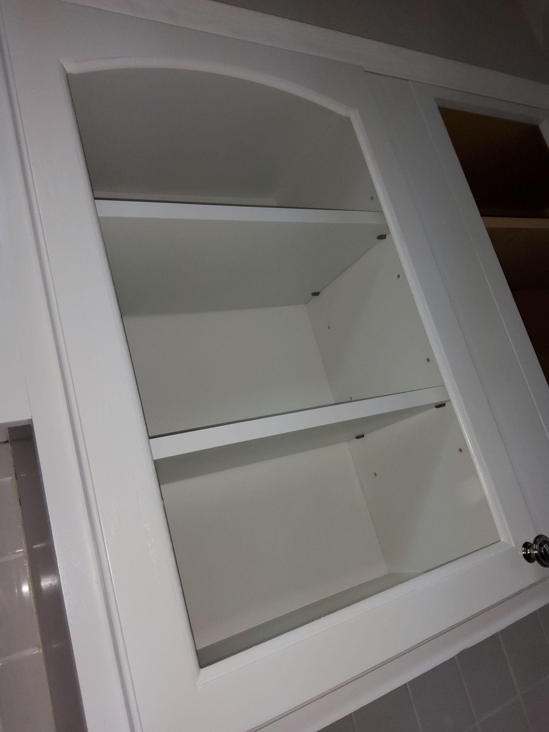 A white cabinet with shelves and a glass door.