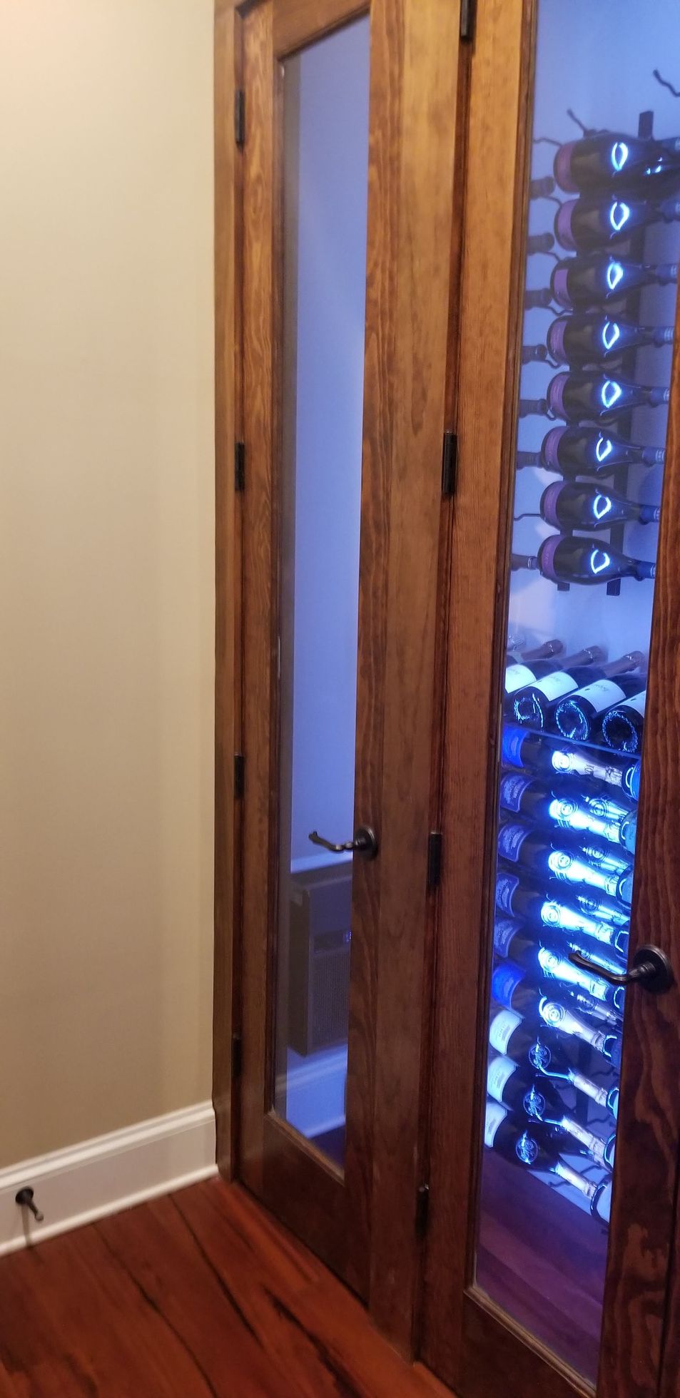 A wine cellar with a glass door and lots of wine bottles.