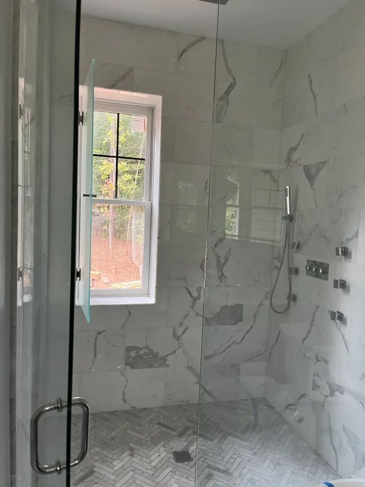 A bathroom with a walk in shower and a window.