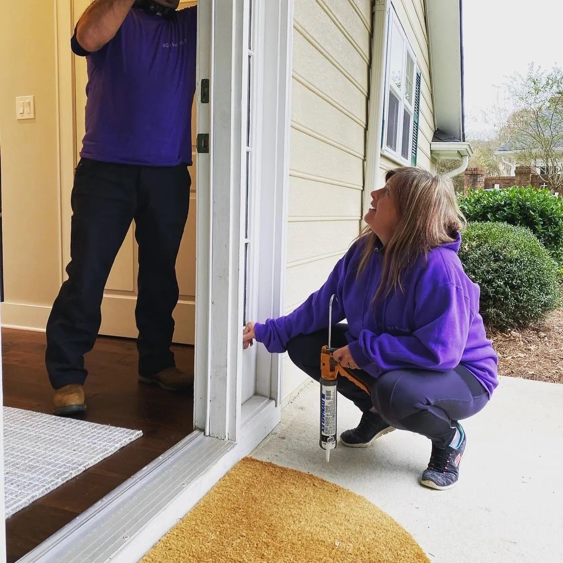 A woman in a purple hoodie is kneeling down next to a man in a purple shirt