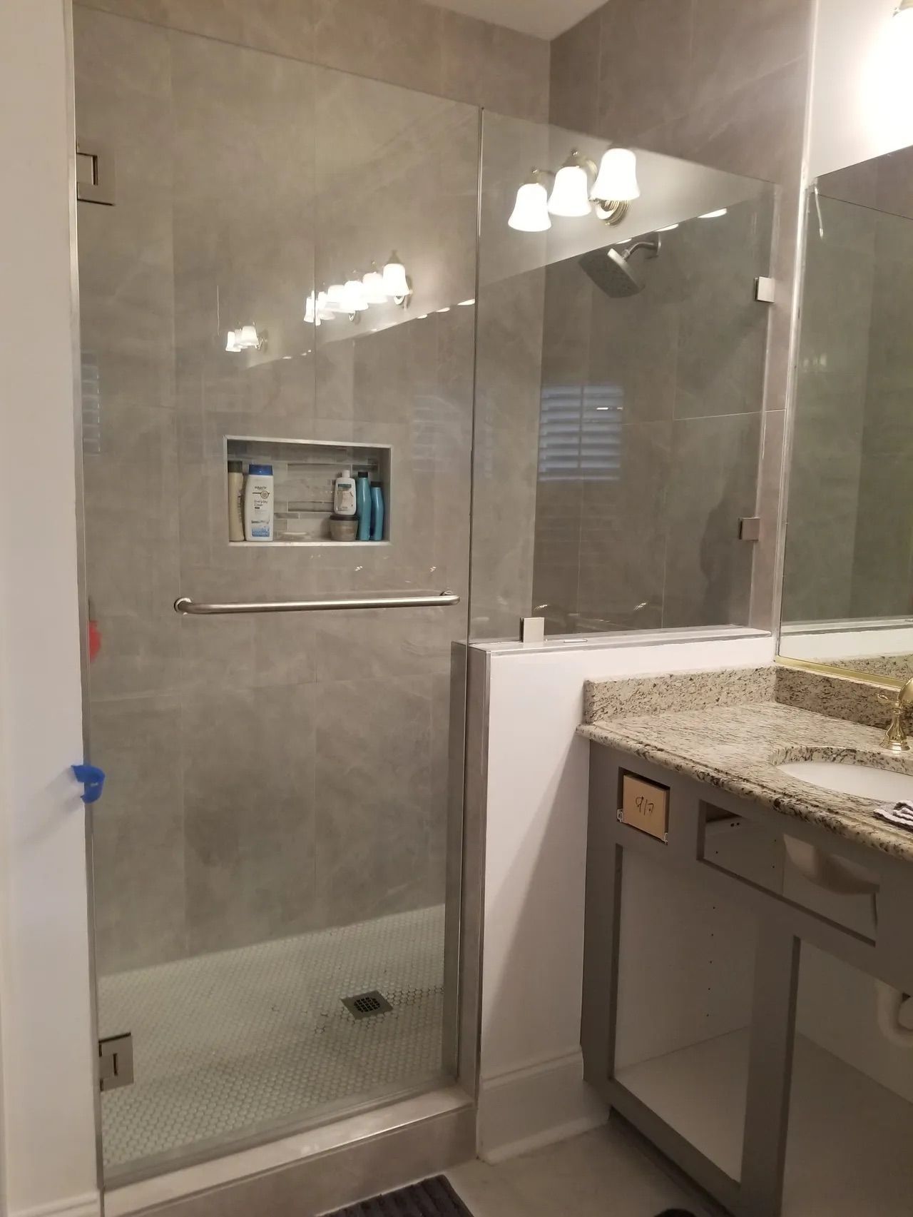 A bathroom with a walk in shower and a sink.